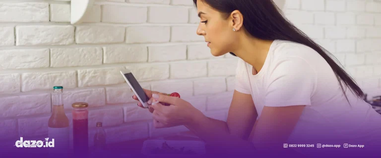 seorang wanita berbaju putih sedang memegang hp. Scrolling aplikasi pemesanan online terbaik