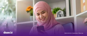 Seorang perempuan berjilbab warna pink sedang memegang hp dengan tangannya untuk Tingkatkan Customer Engagement saat Idul Adha